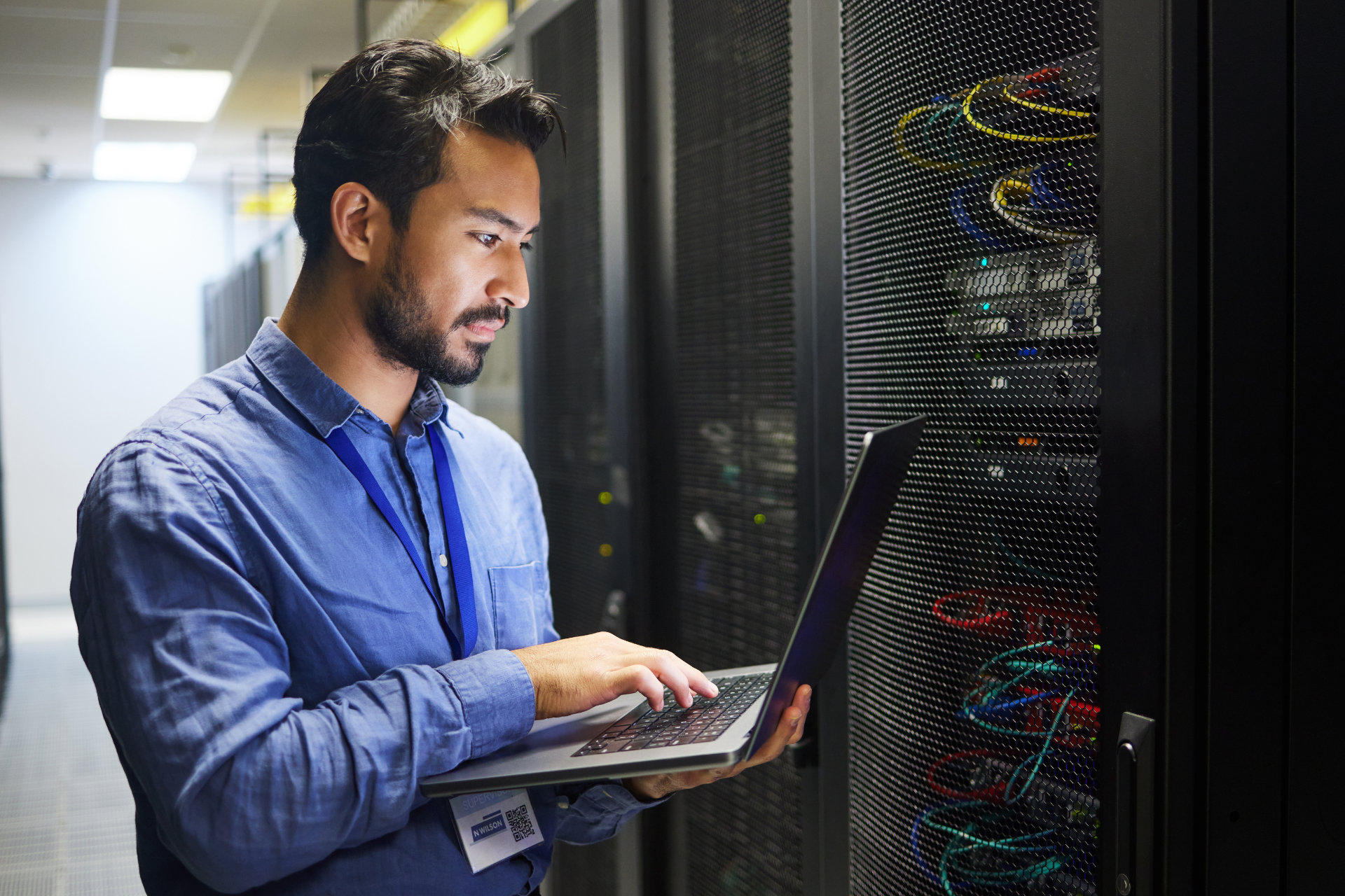 Photo of a man with a laptop in a data center