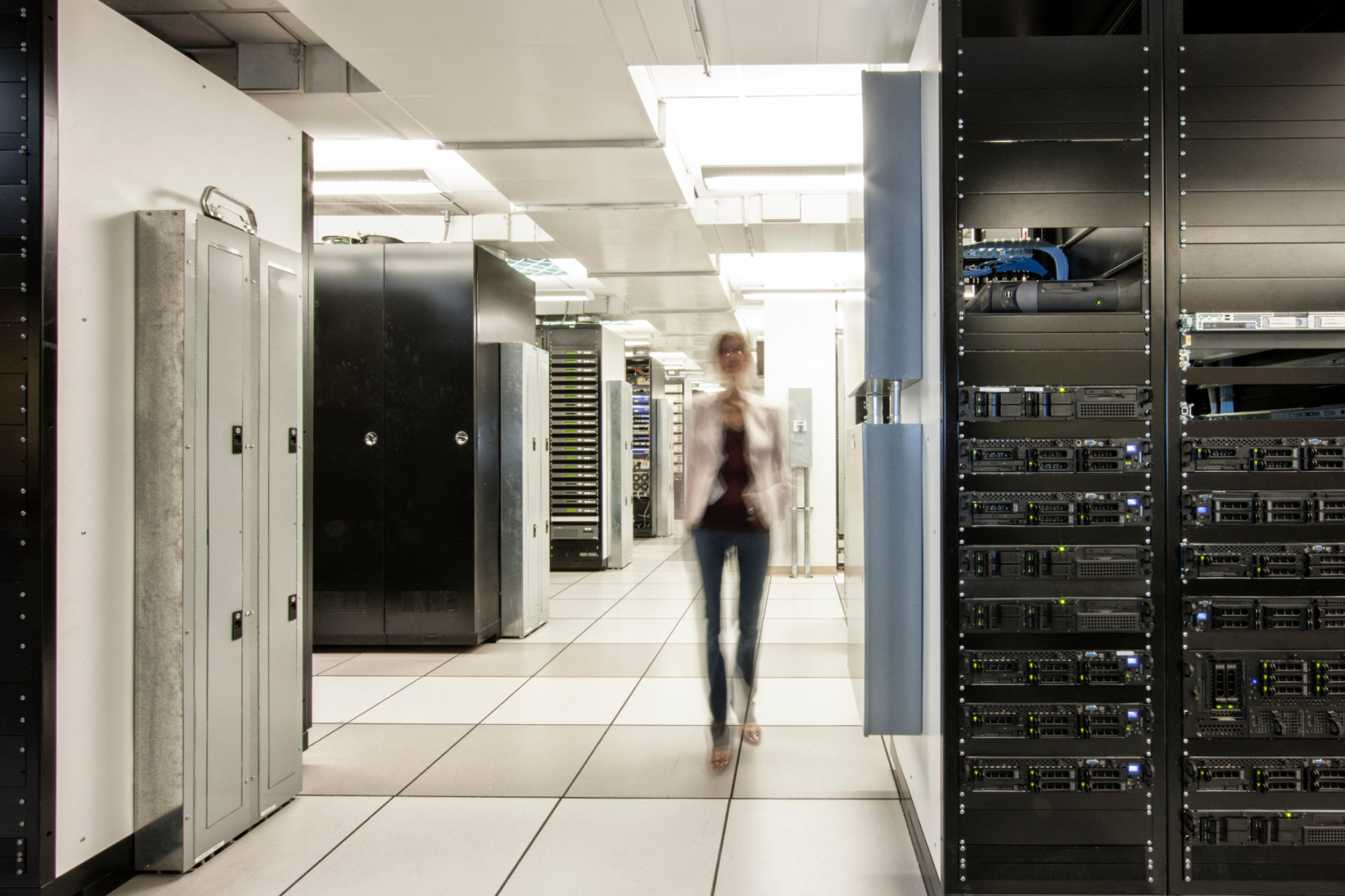 Photo of a slightly blurred woman walking in a data center